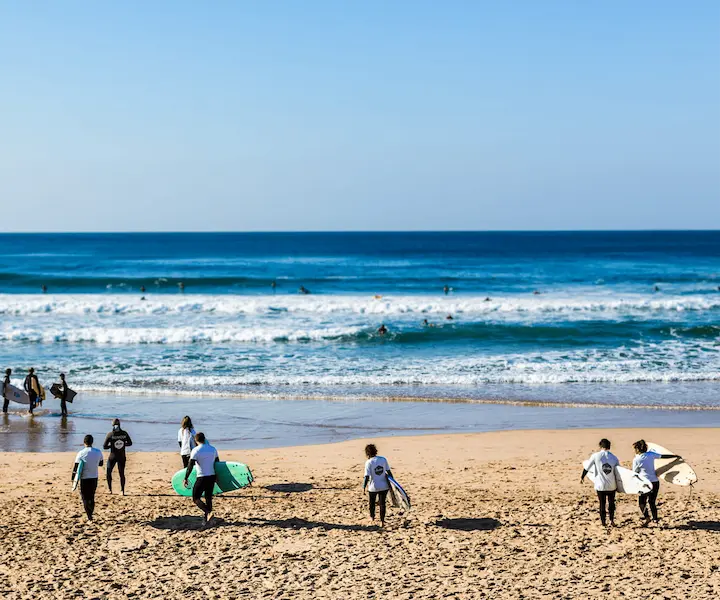 Grupo de alunos a surfar na Costa da Caparica durante uma aula de surf em grupo da Gecko Surf School