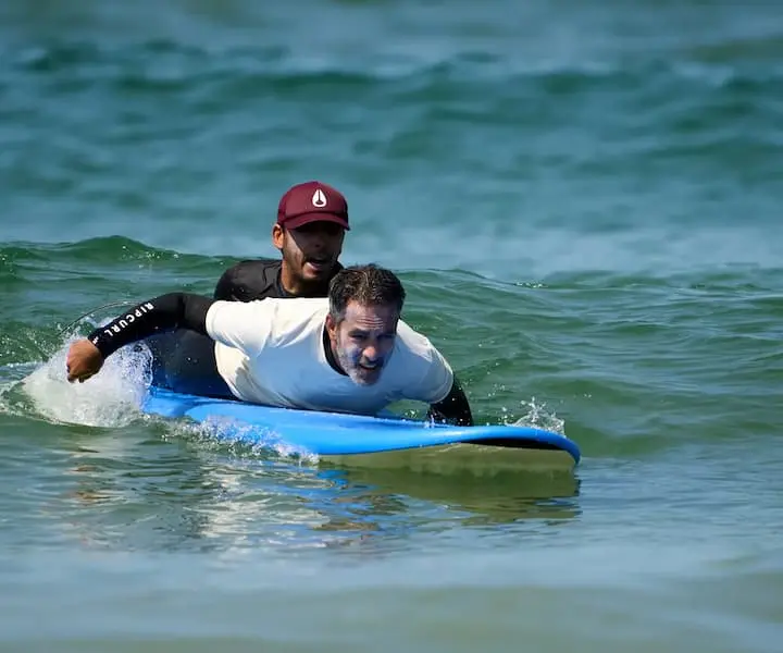 Instrutor a ensinar um aluno a surfar individualmente na Costa da Caparica numa aula de surf privada da Gecko Surf School