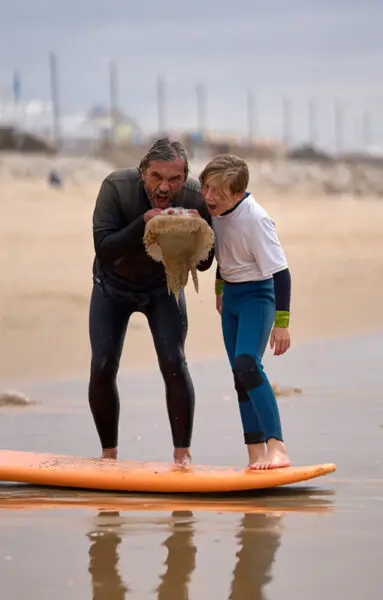 Gecko Surf School instructor teaching a child to surf at Costa da Caparica