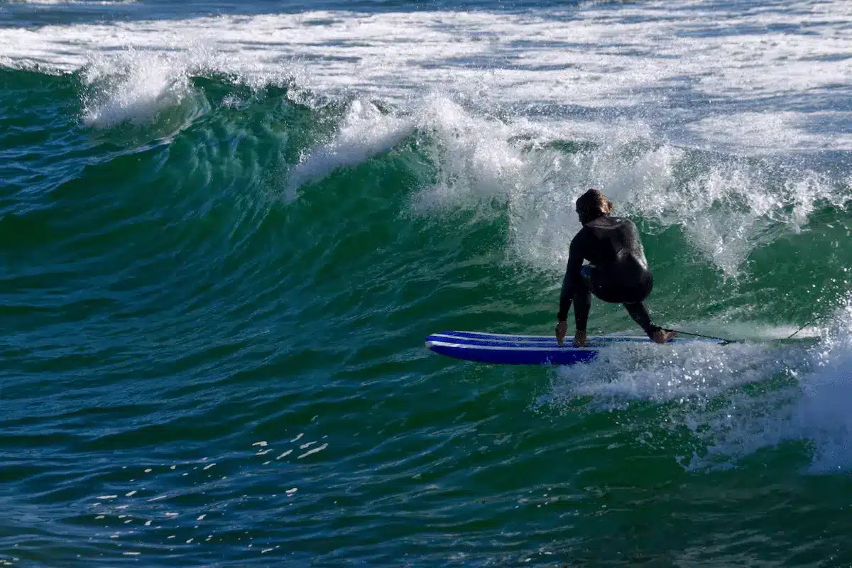 Surfer on a green wave in Costa da Caparica Surfer in a black wetsuit riding a green wave in Costa da Caparica on a blue board