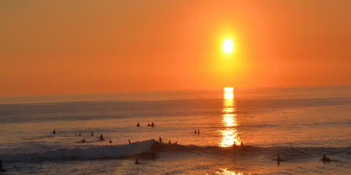 Atlantic sunset with surfers in Costa da Caparica Orange sunset over the Atlantic Ocean in Costa da Caparica with silhouettes of surfers in the waves